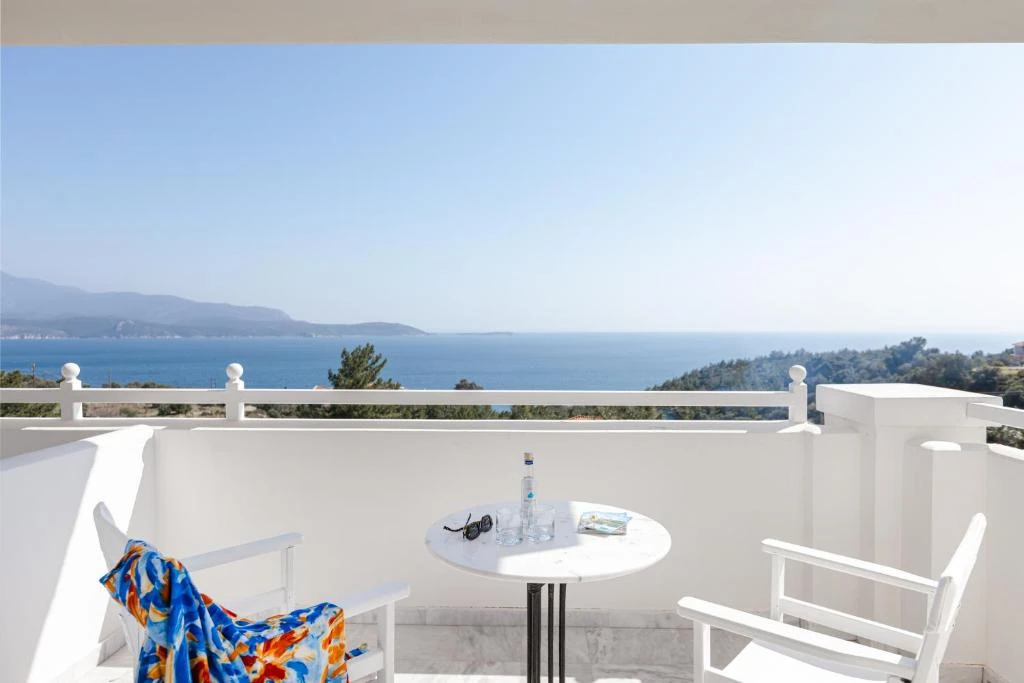 Ευρύχωρο μπαλκόνι με λευκό τραπέζι και ανοιχτή θέα στη θάλασσα.