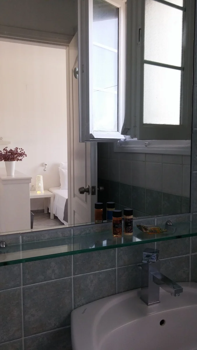 Bathroom washbasin and mirror beneath a window.