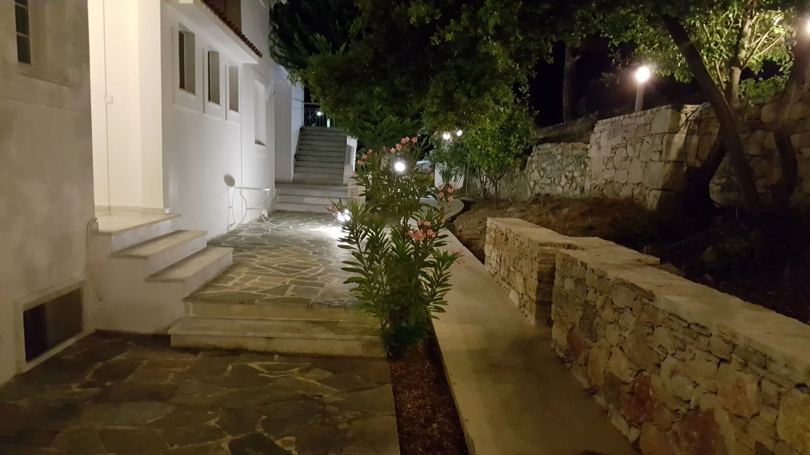 Lit walkway alongside the white building at night.
